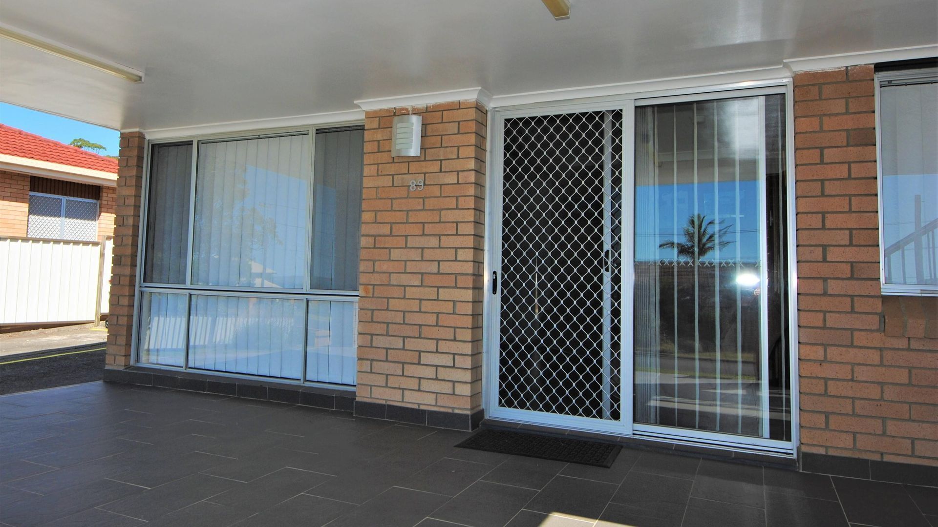 A residential property with a large sliding glass door, a brick exterior, and a tiled patio area.