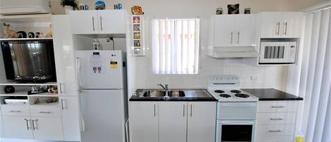 A modern kitchen with white cabinets, a built-in microwave, a stove, and a refrigerator.