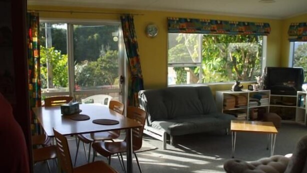 Ein Wohnzimmer mit einer Couch, einem Fernseher und einem Essbereich mit Stühlen und einem Tisch.
