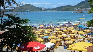 Ein Strand mit vielen gelben Sonnenschirmen und Menschen, die im Wasser entspannen.