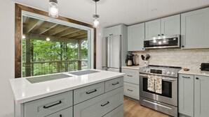 A modern kitchen with a large window, stainless steel appliances, and light grey cabinetry. - Renovated, Foosball, In the trees, EV charger! (Beech Mountain)