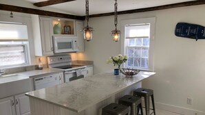 Una cocina moderna con armarios blancos, una isla central con taburetes de bar, un microondas y una estufa.