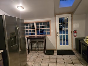 Enjoy meals in the kitchen with a stainless steel refrigerator, dining table, and balcony access.