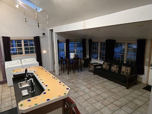 Enjoy cooking in the well-equipped kitchen with a central island, double oven, and dishwasher. Relax in the adjacent living area with a sofa and small table.