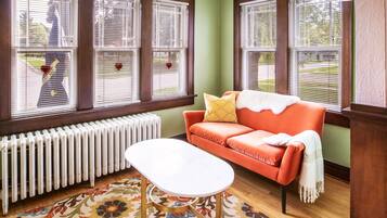 Une pièce chaleureuse avec un canapé rouge, une table blanche et un radiateur.