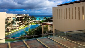 Un resort con una gran piscina, vista al océano y un entorno tropical con palmeras.