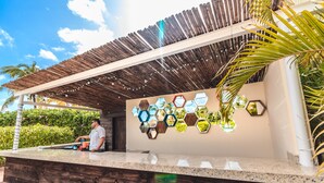 Una recepción con techo de madera, mostrador con superficie de vidrio y pared decorada con espejos hexagonales.