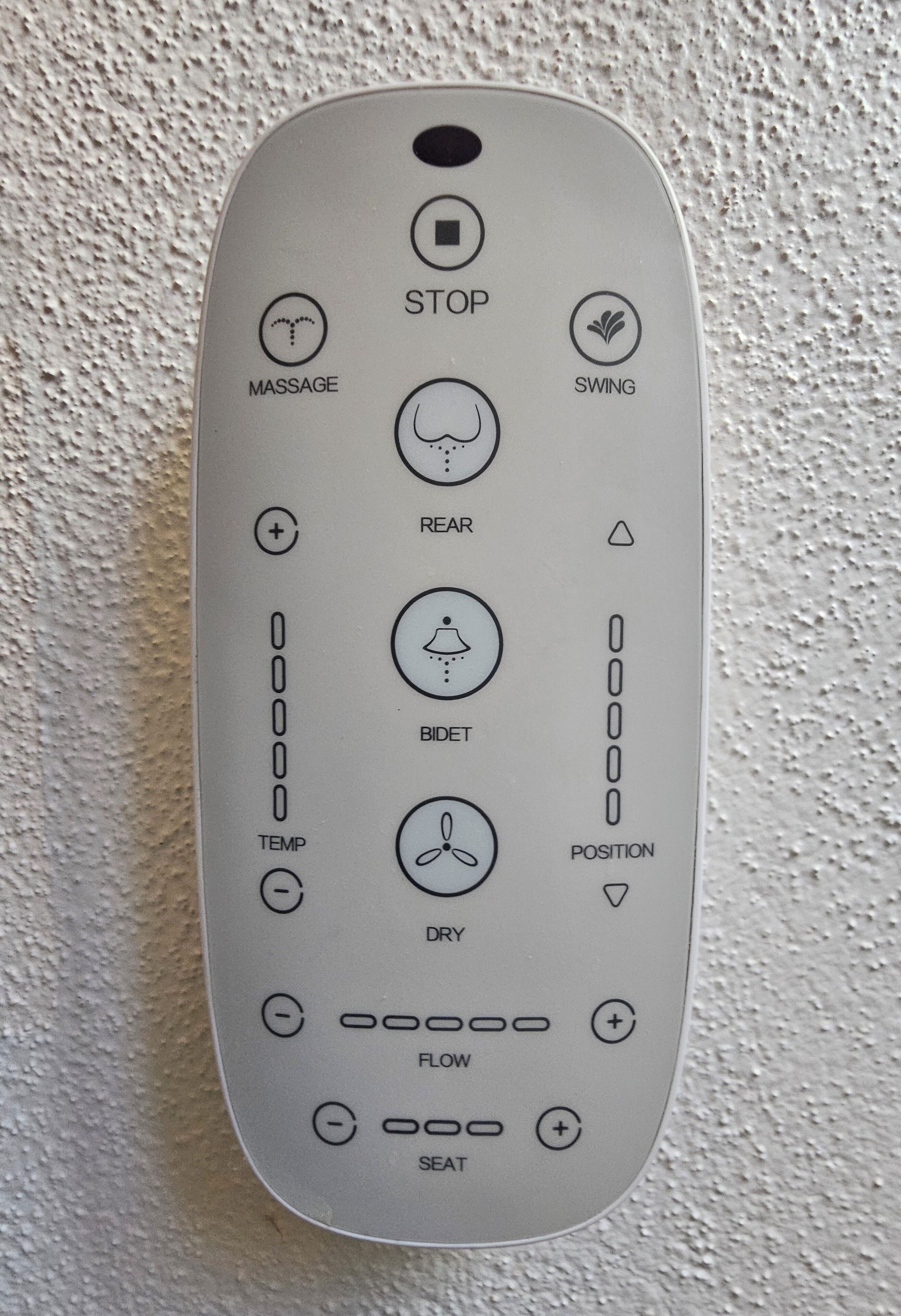 A remote control with various buttons labeled for massage, swing, rear, bidet, temperature, position, dry, flow, and seat.