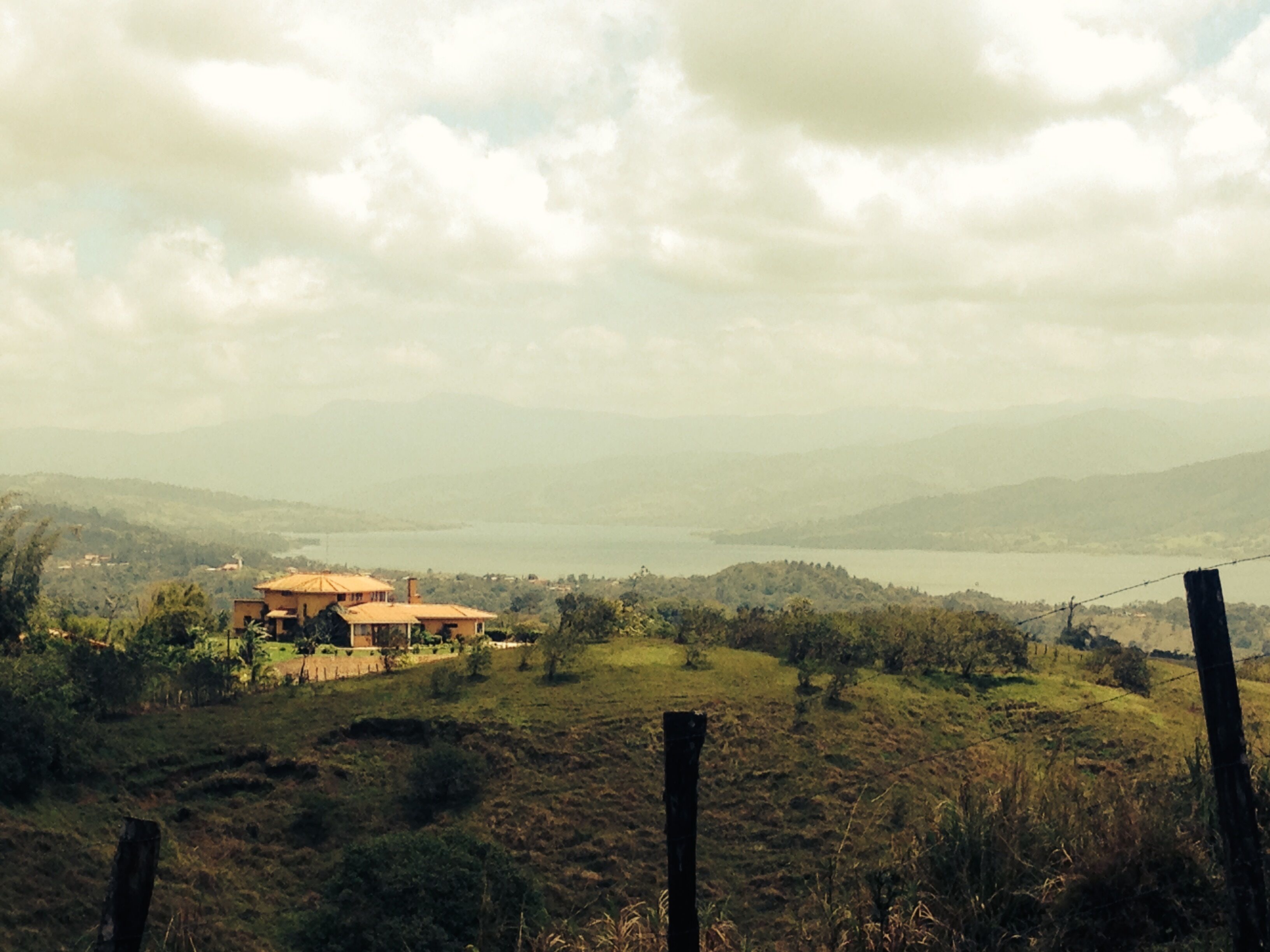 A rural landscape with a house surrounded by fields and hills.