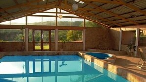A swimming pool with a stone border, large windows, and a covered roof structure. - Simply the best, incredible views, pool, breakfast and a friend in the area! (Nuevo Arenal/Tilaran)