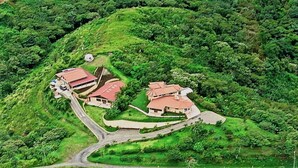 A hillside property with multiple buildings, including a main house and several smaller structures. There is a winding road connecting the buildings. - Simply the best, incredible views, pool, breakfast and a friend in the area! (Nuevo Arenal/Tilaran)