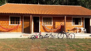 A building with a tiled roof, brick walls, and multiple windows. There are bicycles parked in front. - Enjoy nature in a chalet with a pool, just 200m from the best beach in Ubatuba. (Ubatuba)