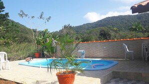 An outdoor swimming pool with a brick wall and potted plants. - Enjoy nature in a chalet with a pool, just 200m from the best beach in Ubatuba. (Ubatuba)