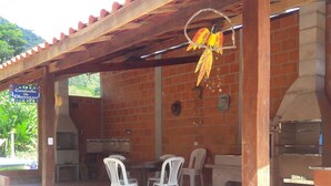 An outdoor patio with brick walls, a pergola, and a hanging birdcage. - Enjoy nature in a chalet with a pool, just 200m from the best beach in Ubatuba. (Ubatuba)