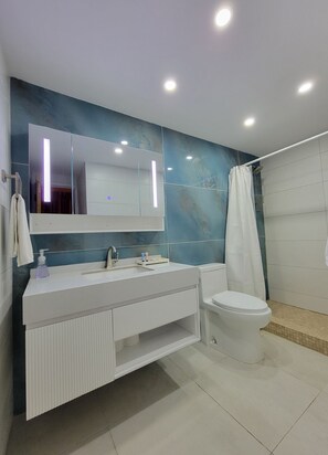 Une salle de bain moderne avec un meuble-lavabo blanc, un grand miroir, des toilettes et un espace douche.