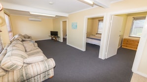 A room with a sofa, a television, and a bed. - Sandy Feet - 31 Gold Coast Drive (CARRICKALINGA)
