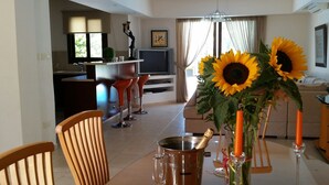 A dining area with a table, chairs, a TV, and a kitchen in the background. - Villa With Private Pool, Sea View With Grass And 2 Gazebos (Pernera)