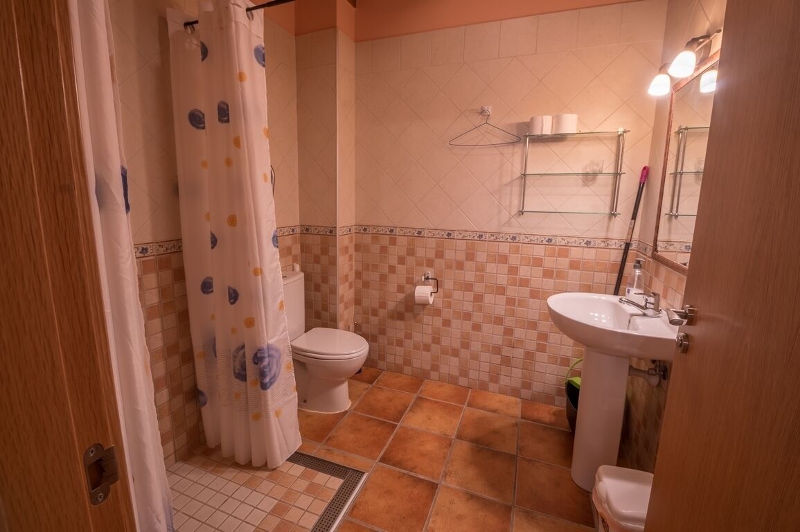 Baño con inodoro, lavamanos y cortina de ducha.
