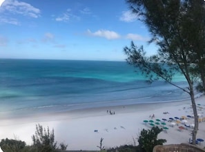A beach with clear turquoise waters, a sandy shore, and umbrellas. - Luxury 3-Bedroom Beachfront Apartment | Sleeps 10. (Praia Grande)