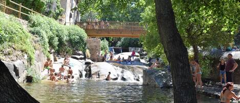 Un área de aguas termales naturales con gente relajándose y nadando.