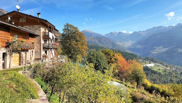 A mountain lodge with a balcony, a view of the valley, and a clear sky.