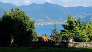 A view of a coastal town with mountains in the background, surrounded by greenery. - PANORAMA Apartment - Large lake view apartment, 2 rooms, 4 places (Solto Collina)
