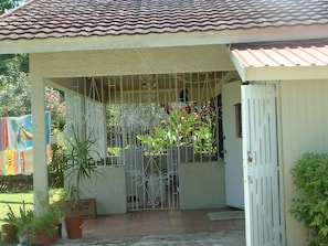 A covered patio with a metal gate, potted plants, and a colorful mural on the wall.