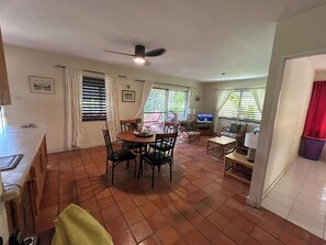 A spacious living area with a dining table, chairs, a television, and a ceiling fan.