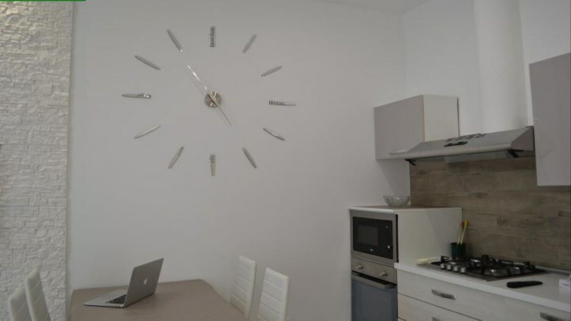 Una cocina moderna con un reloj integrado, estufa y microondas.