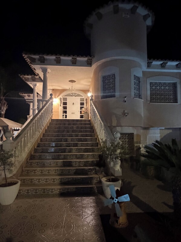 A grand staircase leading to a white building with a balcony, columns, and a door at the top.
