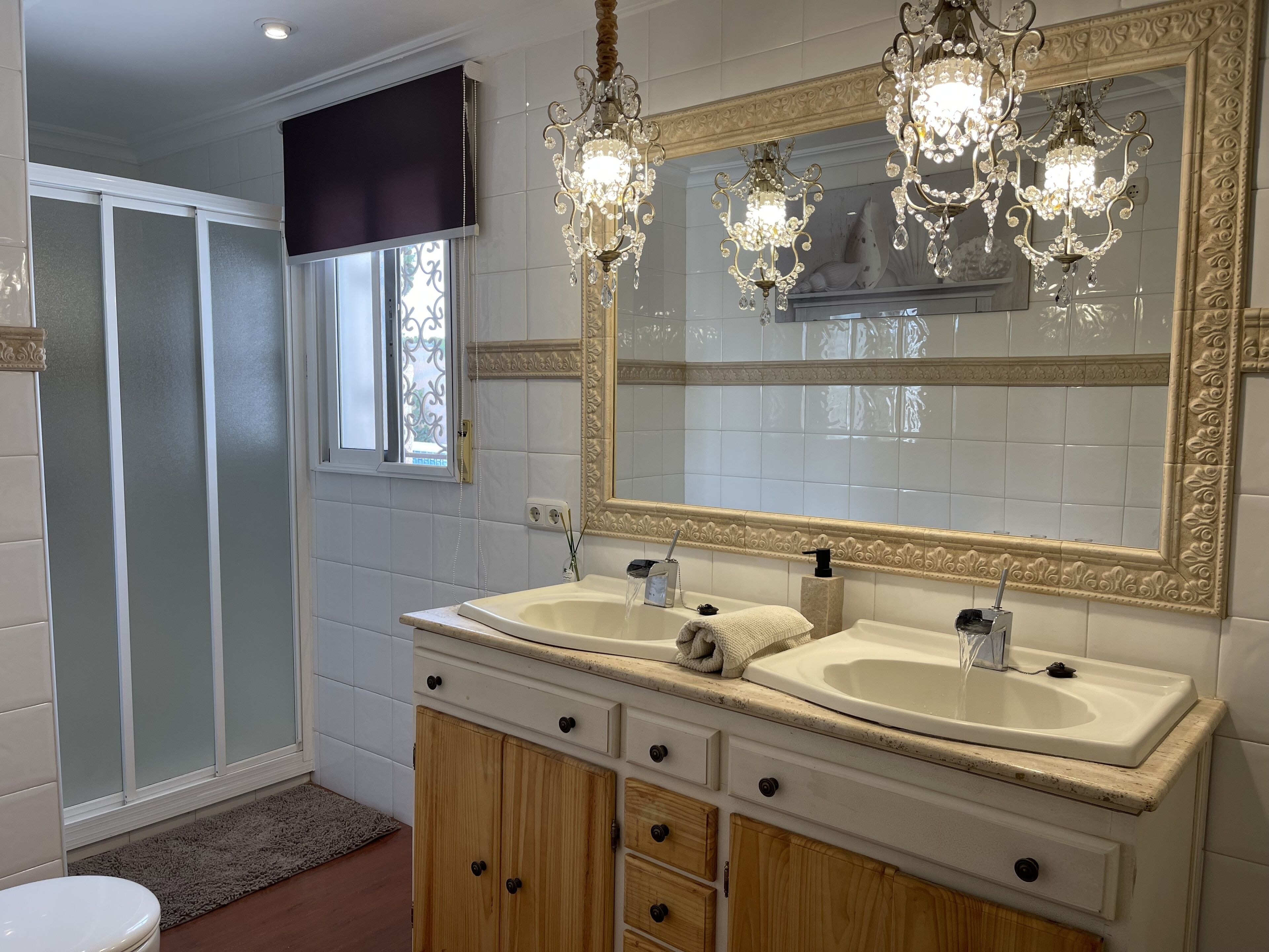 A bathroom with two sinks, a large mirror, and a shower area.