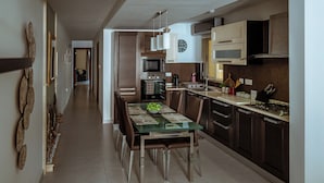Et moderne køkken med spiseplads, med et glasbord, træstole og stålemmer.