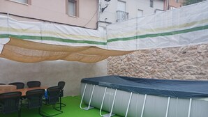 Un espace extérieur aménagé avec une table et des chaises, un trampoline et un sol recouvert d’herbe.