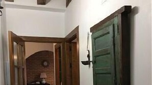 Un couloir avec un radiateur, une étagère remplie de livres et une porte verte.