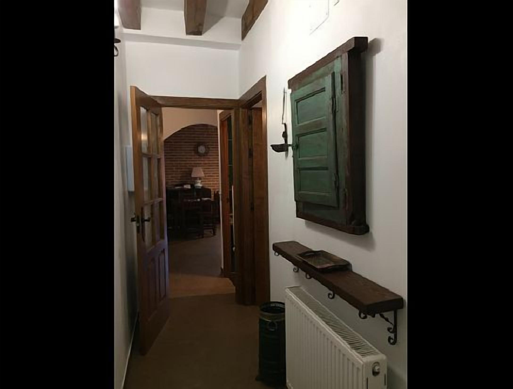 Un pasillo con un radiador, una estantería con libros y una puerta verde.