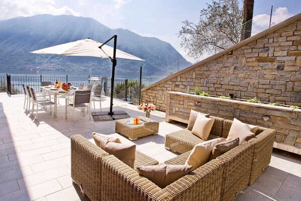 An outdoor patio with wicker furniture, a table with chairs, and a large umbrella.
