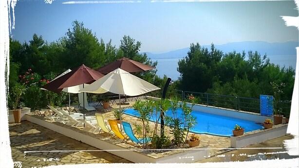 Un área de piscina con sombrillas, sillones reclinables y un tobogán.