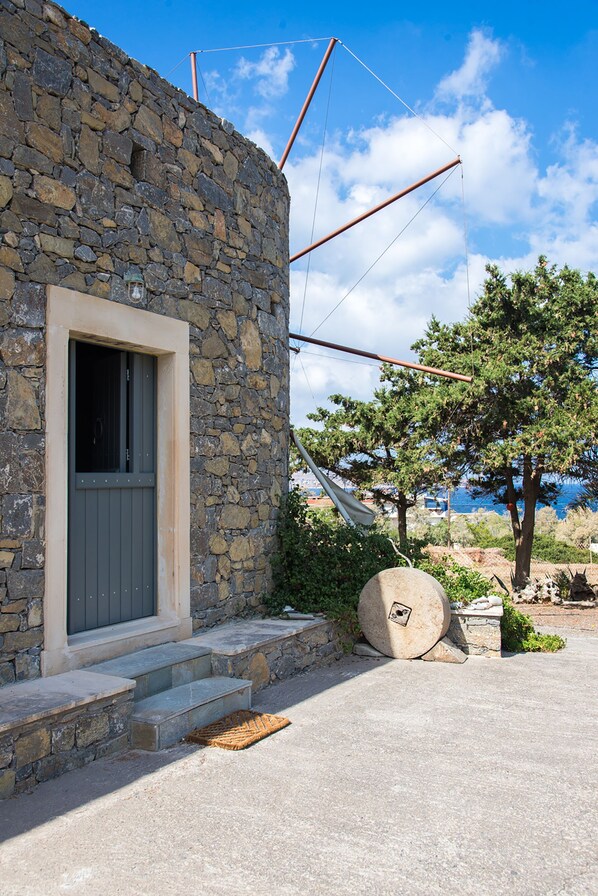 Ein Steinhaus mit einer grauen Tür und Stufen, die davorführen.