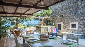 An outdoor dining area with a stone wall, wooden table, and chairs.