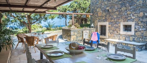 An outdoor dining area with a stone wall, wooden table, and chairs.