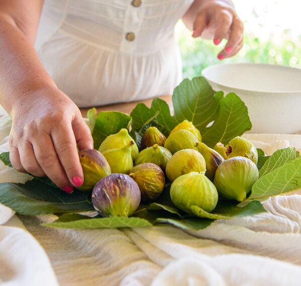 A person handling figs on a table with a bowl nearby. - An authentic stone Cretan windmill (Sitia)