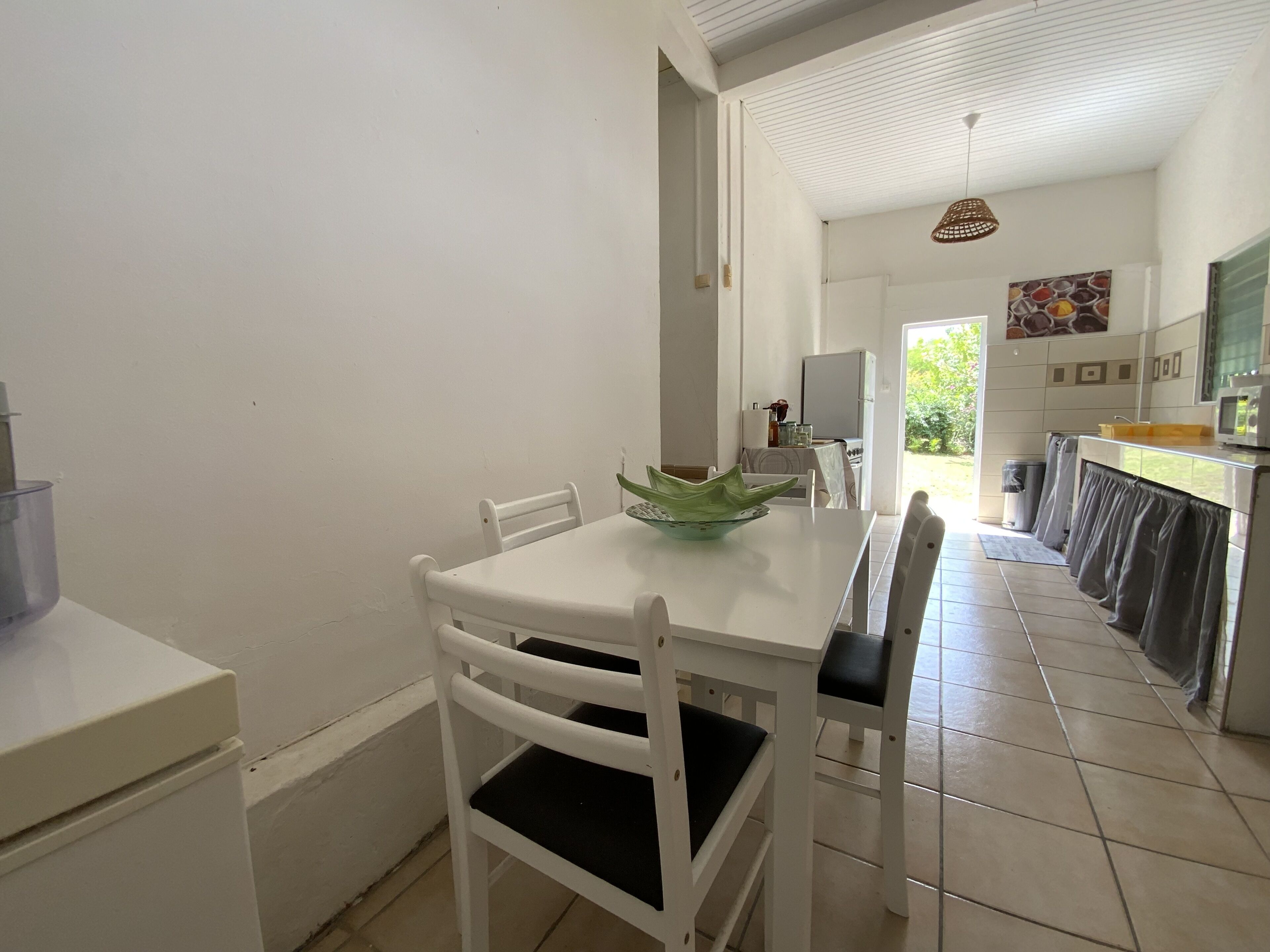 Una cocina limpia y moderna con armarios blancos, una mesa de comedor con sillas y vistas al área de estar contigua.