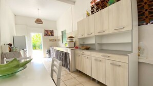Una cocina moderna con armarios de madera clara, una encimera blanca y un tazón verde sobre la mesa.