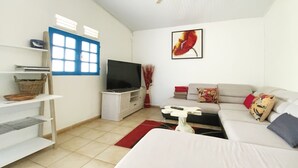Una sala de estar moderna con un televisor de pantalla plana, un sofá, una mesa de centro y un mueble para la televisión.