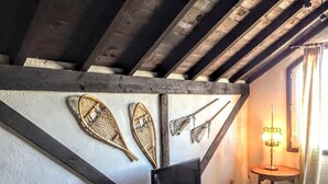 Une pièce avec un plafond en bois, un téléviseur posé sur une petite table et des éléments décoratifs accrochés aux murs.