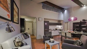 A modern living room with a sofa, a coffee table with candles, and a dining area with a table set for four.