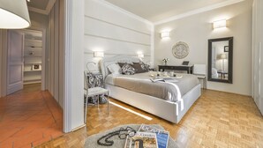 A modern bedroom with a large bed, bedside tables, a desk, and a wardrobe.