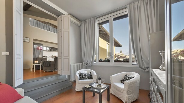 A spacious living room with a view of the city, a dining area, and a kitchen.