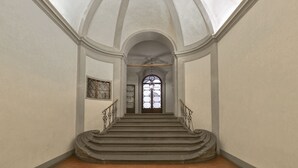 A grand staircase with a high ceiling and a large arched window at the top.