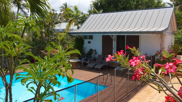 A poolside area with a pool, lounge chairs, and a small building with a sloped roof.